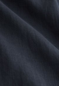 Tissu bleu marine foncé avec des plis doux et un tissage lisse, légèrement texturé, visible en gros plan.