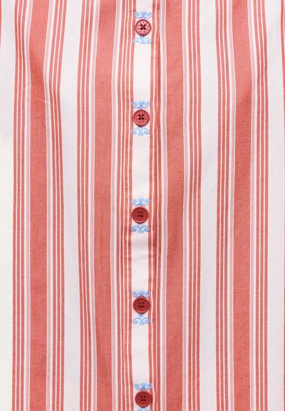 Vertikaalselt punase ja valge triibuline kangas kuue punase nupu ja siniste tikanditega lilleliste detailidega nupurida ääres.