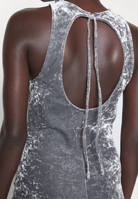 Robe en velours gris avec un dos ouvert, dotée d'une fermeture à nouer, d'une texture douce et d'un motif marbré subtil.