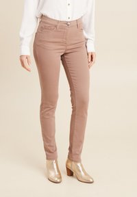 Lichtbruine slim-fit jeans met een hoge taille, lichte stretch, voorzakken en een gladde textuur, gecombineerd met metallic enkellaarsjes.
