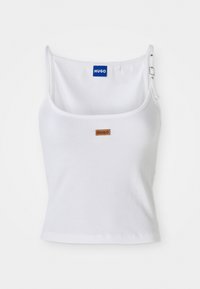 Valge nööriga tank top reguleeritavate rihmadega, millel on sinine logo silt ja väike pruun silt, valmistatud pehmest ja venivast materjalist.