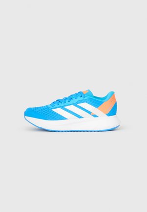 Zapatillas deportivas azules con parte superior de malla tipo panal, detalles blancos, lengüeta naranja en el talón y suela texturizada. Presentan tres franjas diagonales blancas.