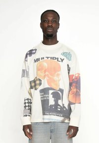 Langärmliges Grafik-Sweatshirt in Elfenbein mit bunten Drucken, darunter Totenköpfe und Text. Baumwollmischung mit lockerer Passform und Rundhalsausschnitt.