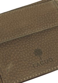 Porte-cartes en cuir marron avec une surface texturée. Présente un logo subtil avec un motif d'arbre et des coutures visibles le long des bords.