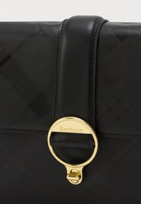 Fekete bőrtáska steppelt mintával, aranyszínű fém kiegészítő kerek csattal és sima felülettel a szélein.