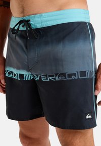 Shorts de bain pour hommes avec un design dégradé allant du bleu foncé au bleu clair, dotés d'une taille noire, d'un cordon de serrage et d'accents de logo.