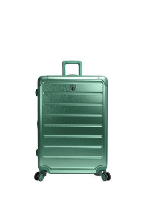 Valigia rigida verde con maniglia estensibile e quattro ruote doppie pivotanti, in piedi su sfondo bianco.