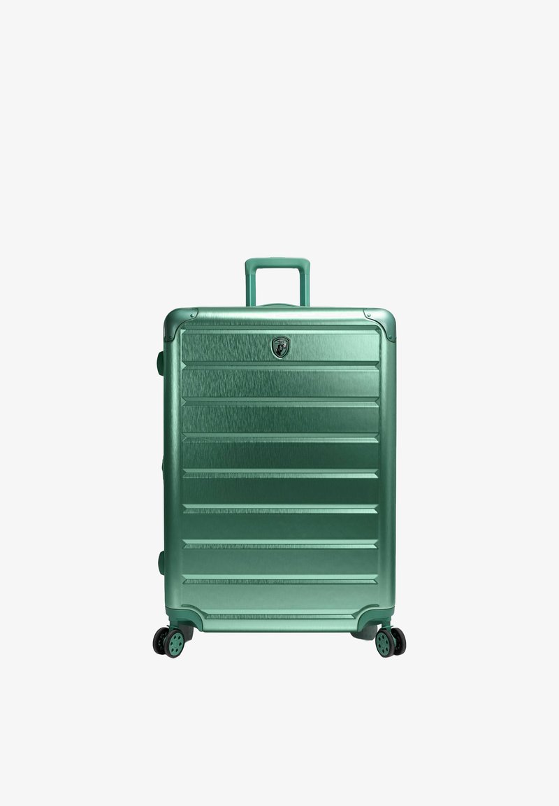 Valise rigide verte avec poignée extensible et quatre roues doubles pivotantes, debout sur un fond blanc.