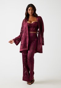 Bordeaux loungewear set met een bloemenkant overlay, een cropped top met beugels en comfortabele broek. Verfraaid met elegante details.