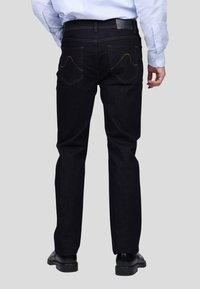 Jeans en denim foncé avec une coupe droite, comportant des surpiqûres orange contrastées, deux poches arrière et une taille lisse.