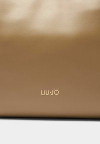 Borsa marrone in ecopelle con una texture liscia, caratterizzata da un logo discreto in oro. Design minimalista senza parti metalliche o dettagli visibili.