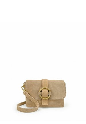Petit sac bandoulière en daim beige avec une sangle avant comportant une grande boucle circulaire dorée et une bandoulière ajustable.