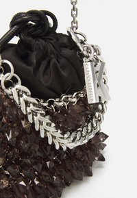 Czarna satynowa torba na sznurku z dekoracyjnym frędzlem z fasetowanych ciemnofioletowych ozdób. Posiada srebrny łańcuszek i metkę z napisem "KARL LAGERFELD."