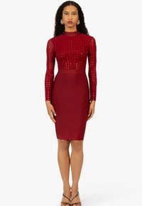 Rotes, tailliertes Kleid mit einem durchsichtigen Langarm-Oberteil, das mit Pailletten verziert ist, einem hohen Halsauschnitt und einem glatten Bleistiftrock, ergänzt durch dünne Träger.