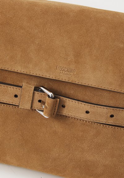 Geantă din suede maro cu o textură netedă, având o curea cu cataramă și un logo embosat "Moschino Milano". Design simplu, rectangular.