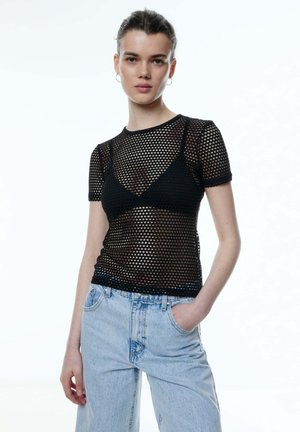 Zwart mesh shirt met korte mouwen, voorzien van een aansluitend ontwerp en een ruitpatroon, gecombineerd met lichtblauwe denim jeans met hoge taille.