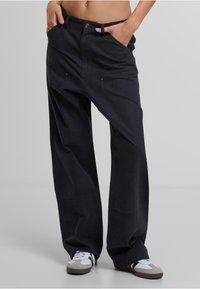 Pantalones de pierna ancha en algodón negro, con dos bolsillos frontales, un cierre de botón y un corte informal para mayor comodidad. Tejido texturizado con detalles de costura.