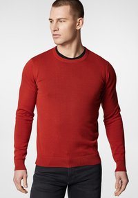 Czerwony sweter z dzianiny z okrągłym dekoltem i prążkowanymi mankietami, dopasowany krój oraz gładka tekstura, zestawiony z ciemnymi dżinsami.