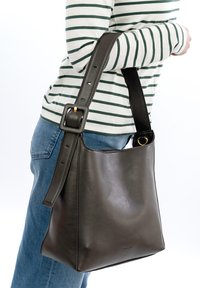 Brązowa skórzana torebka na rami�ę o gładkiej fakturze, z regulowanym paskiem i złotym akcentem na pasku.