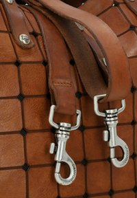 Bruine leren tas met een gridontwerp en een gestructureerde oppervlakte. Voorzien van zilveren metalen hardware en clips bevestigd aan een bruine schouderband.