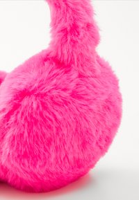 Casque moelleux de couleur rose vif avec une forme arrondie et une texture duveteuse, composé de matériau en fourrure douce pour un confort accru.
