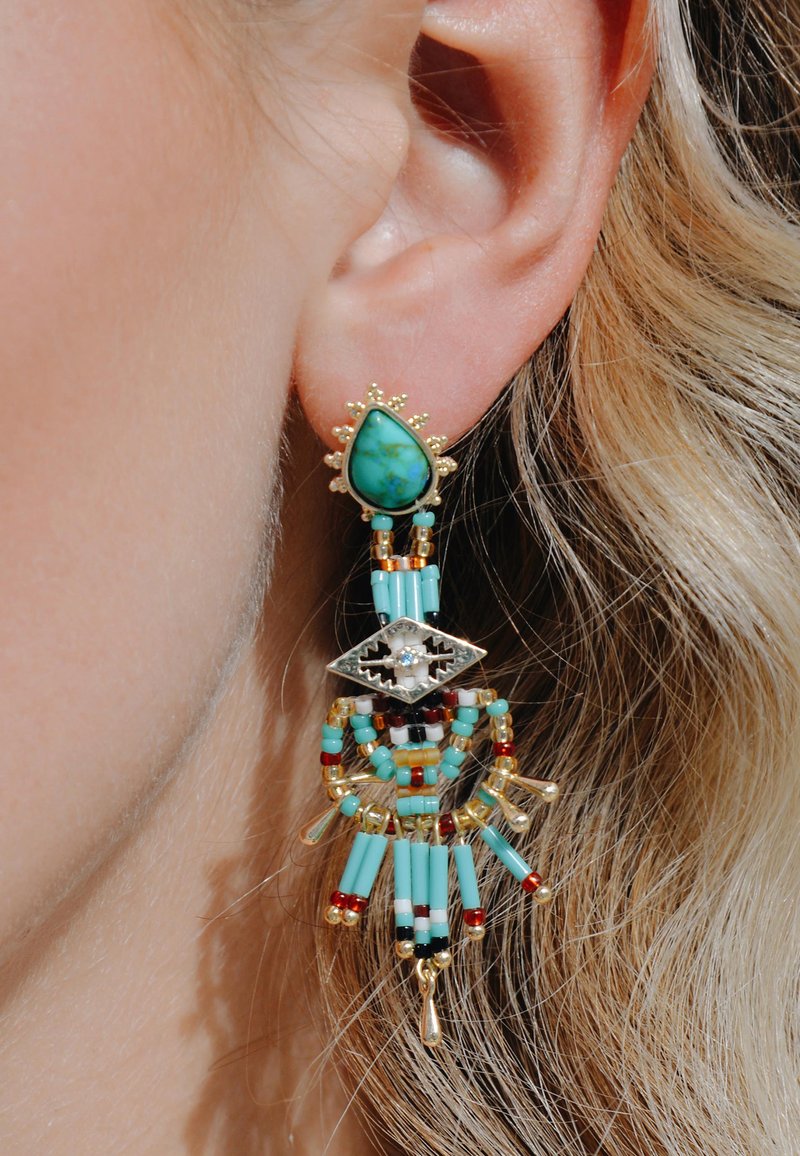 Boucles d'oreilles en perles turquoises avec des accents dorés. Présentent une pierre en goutte d'eau, un travail de perles complexe et des éléments pendants de différentes couleurs.