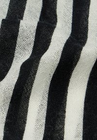 Tekstil med svart og hvite striper, som har en vevd, teksturert overflate. Stripene alternerer i bredde, noe som skaper et dristig, kontrasterende mønster.