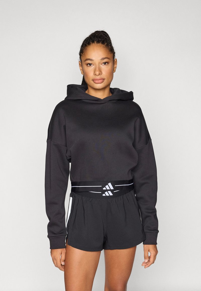 Zwarte hoodie met losse pasvorm, gecombineerd met zwarte sportshorts met een elastische tailleband met merknaam en zijaccenten.