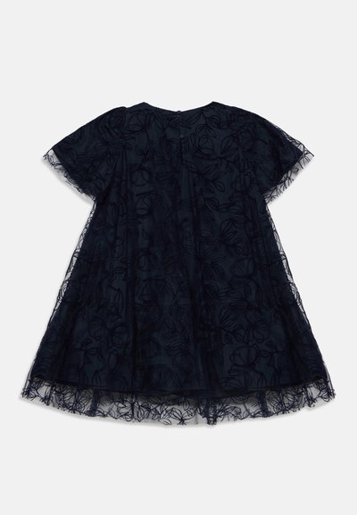 Robe courte bleu marine avec superposition en dentelle florale transparente, manches courtes, col rond et boutons dans le dos au centre.