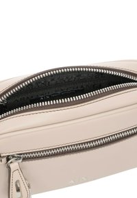 Borsa in pelle rosa chiaro con una finitura testurizzata, dotata di una chiusura con zip argentata e Accenti marroni a contrasto. L'interno presenta un motivo con il logo.