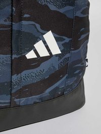 Mochila de camuflaje azul y negra con un acabado texturizado, que presenta un logo de Adidas en blanco en un panel lateral y una base negra.