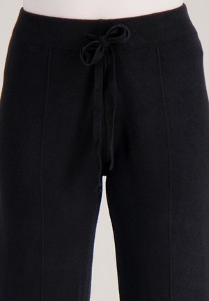 Zwarte gebreide joggingbroek met een aansluitende tailleband, verstelbare trekkoord en zijnaden. Zachte textuur en een losse pasvorm voor comfort.
