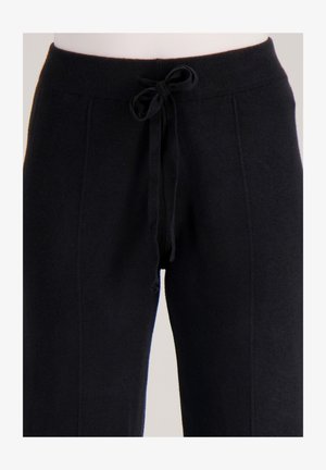 Zwarte gebreide joggingbroek met een aansluitende tailleband, verstelbare trekkoord en zijnaden. Zachte textuur en een losse pasvorm voor comfort.