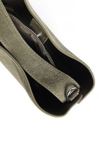 Olijfgroene suède tas met een gestructureerde afwerking, voorzien van een zilveren rits, lederen interieur en een gladde schouderband met een metalen ring.