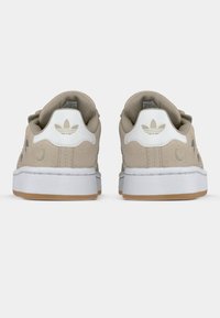 Bézs színű, velúr sportcipő fehér részletekkel és gumitalpakkal. Klasszikus kialakítású, oldalt és a saroknál hímzett márkajelzéssel.