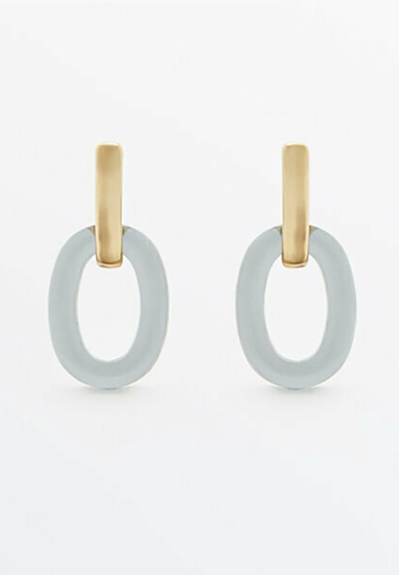 Clous rectangulaires dorés avec des anneaux ovales gris mats attachés formant des boucles d'oreilles pendantes modernes sur fond blanc.