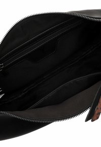 Interno di una borsa nera con zip che mostra una finitura lucida e liscia, due tasche con zip e una fodera in tessuto testurizzato con un motivo sottile.