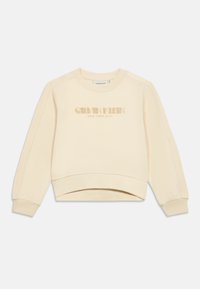 Felpa color crema realizzata in tessuto morbido. Presenta un collo rotondo, spalle basse e un logo luccicante "Calvin Klein NEW YORK CITY".