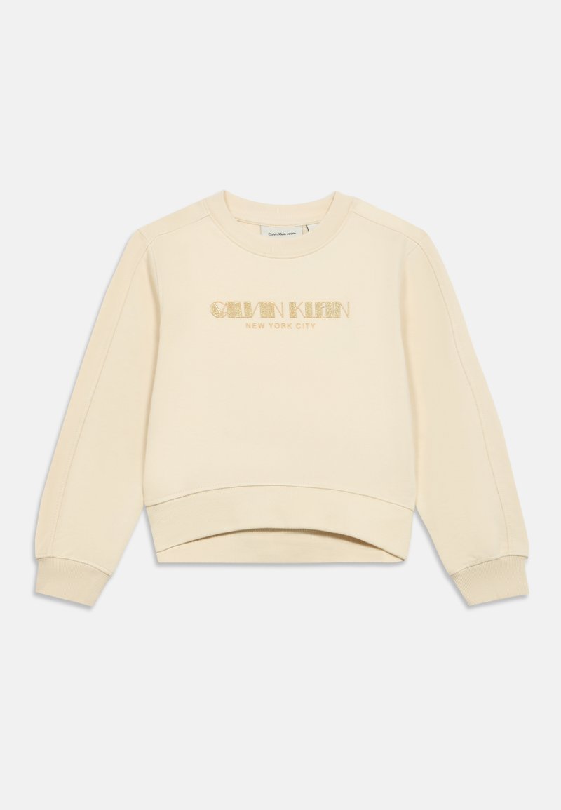 Felpa color crema realizzata in tessuto morbido. Presenta un collo rotondo, spalle basse e un logo luccicante "Calvin Klein NEW YORK CITY".