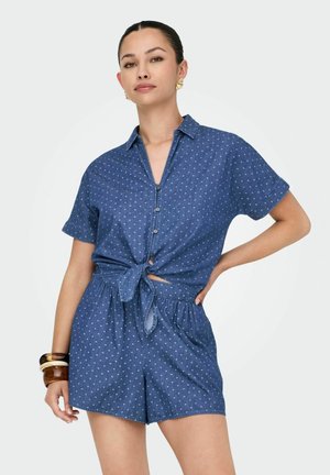 Jeanshemd- und Shorts-Set in Blau mit weißen Punkten. Beinhaltet eine Knopfverschluss, Kragen und ein geknotetes Frontdetail.