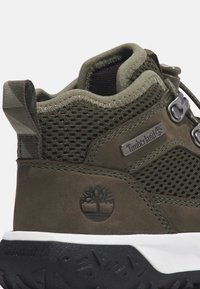 Gröna mocka- och meshsandaler för vandring med en texturerad svart gummisula, silverdetaljer och en logotyp-patch. Har en vadderad krage och en dragögl.