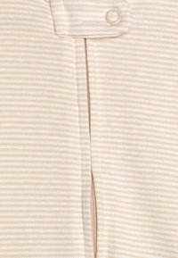 Tissu beige à rayures présentant une fermeture éclair proéminente et un bouton-pression, avec une texture douce et un motif subtil de fines rayures.