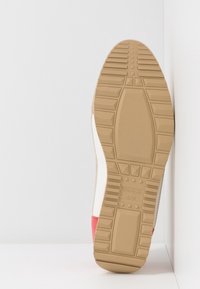 Sulan har en gummitextur i ljusbrunt med en vit kant och röda detaljer. Innehåller präglat varumärke och storleksinformation.