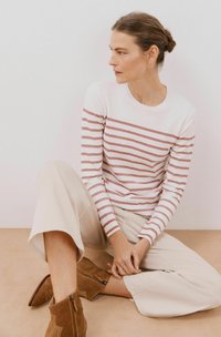 Gestreepte gebreide top in wit en stoffige roze, gecombineerd met lichte beige wijde broek en bruine suède enkellaarsjes met een rits.