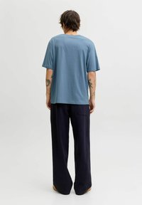 Lühikeste varrukatega sinine puuvillane t-särk ümara kaelusega; kombineeritud mustade laiade pükstega, millel on tagatasku ja lõdva istuvusega.