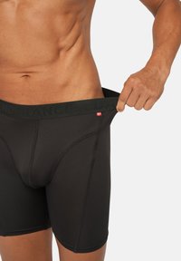 Schwarze Stoff-Boxershorts mit breitem Bund, der mit "ENDURANCE" beschriftet ist, und einem kleinen dänischen Flaggenlabel. Glatte Textur und enganliegendes Design.