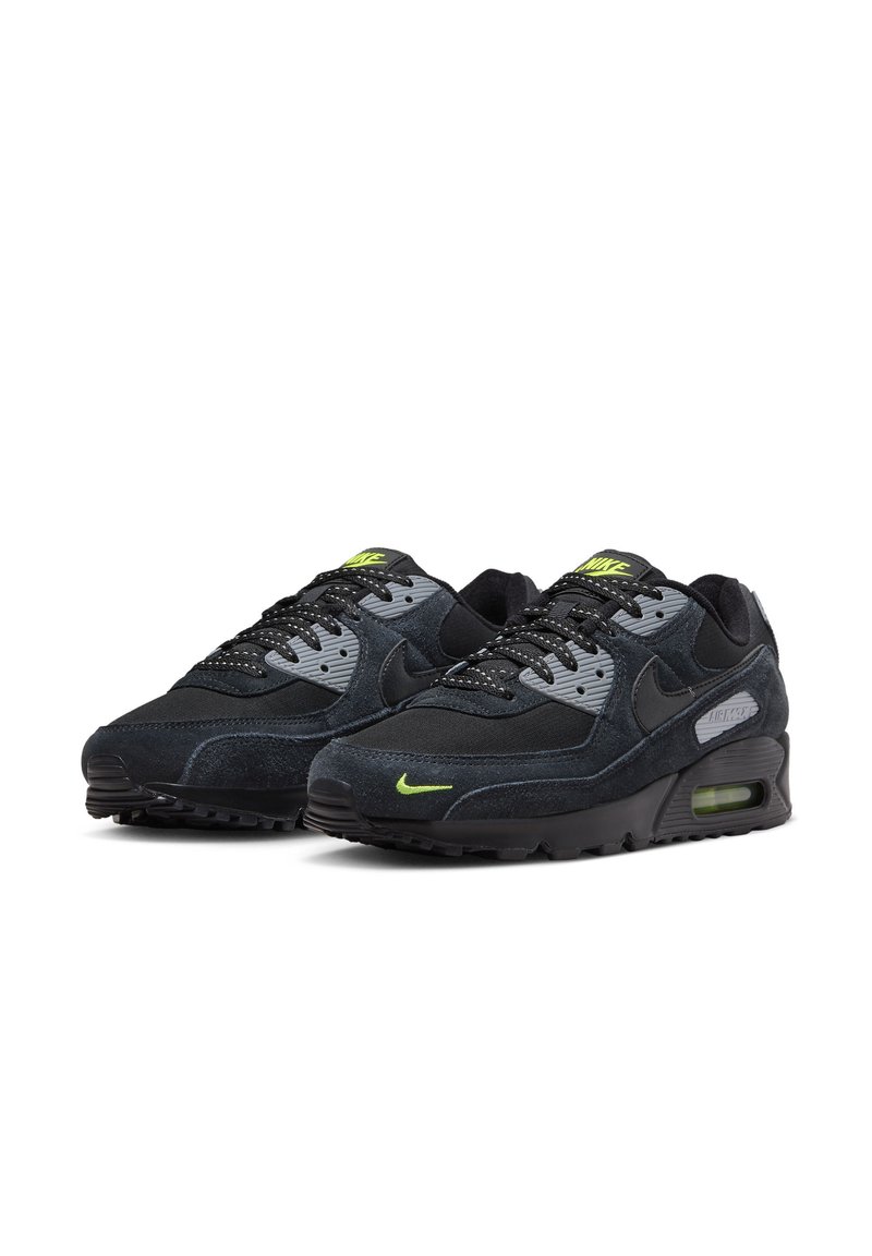 Zapatillas Nike Air Max 90 en cuero de gamuza negro y gris con detalles verdes; cuentan con una suela acolchada, paneles de malla texturizada y un diseño con cordones.