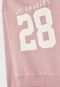 Felpa rosa con la scritta "LOS ANGELES" in bianco sopra il numero "28" in un grande carattere bianco. Materiale morbido con orlo a coste.