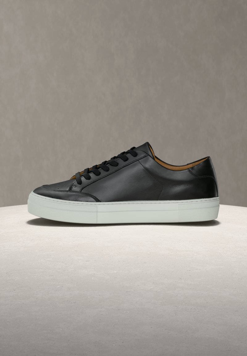 Μαύρο δερμάτινο αθλητικό παπούτσι με λεία υφή, με μαύρα κορδόνια, λευκή λαστιχένια σόλα και εσωτερικό καφέ δέρμα ως διακοσμητικό στοιχείο.