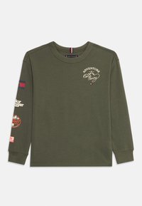 Donkergroen, lange mouwen shirt met de tekst "Avontuur bij Kamp Tommy" en kleine logo's op de borst en mouw, ronde hals, van katoen.